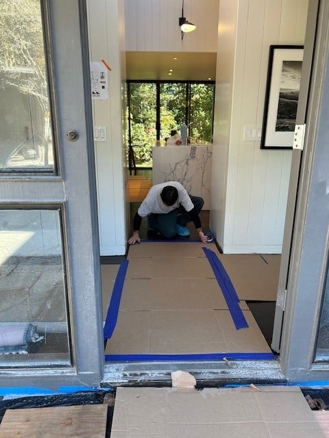 A worker is protecting the floor of a home prior to deliveries coming in